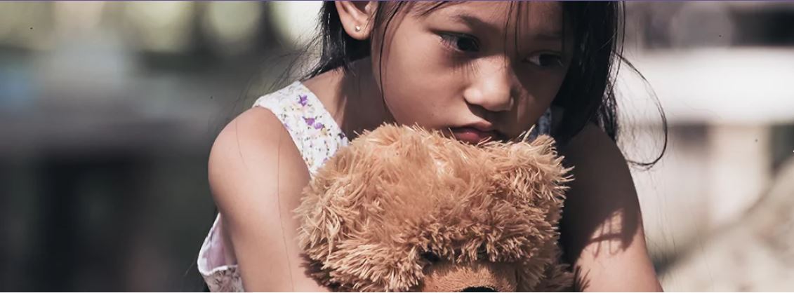 Child hugging stuffed bear.