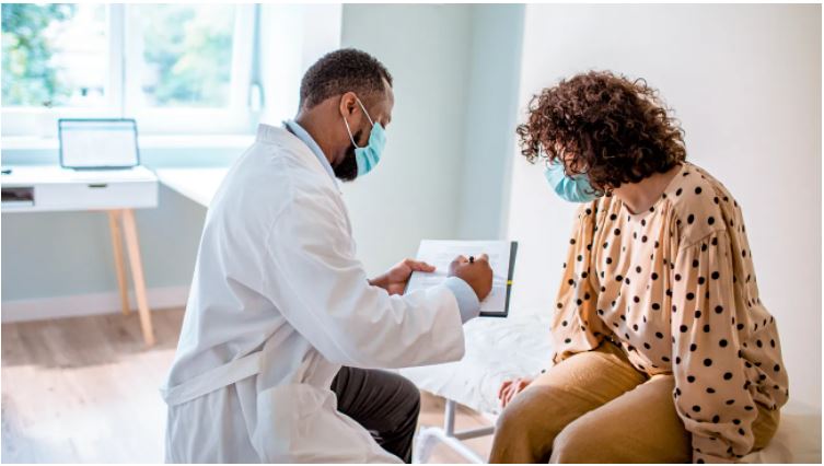 Women sitting on an exam table while looking at a chart with a physician.